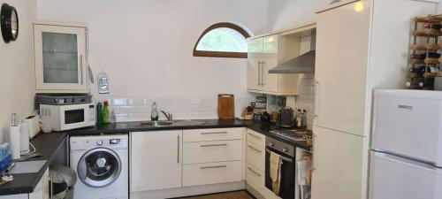 a kitchen with white cabinets and a washer and dryer at maison de vacances in Quend