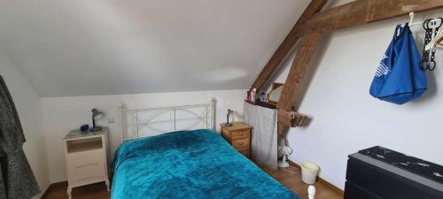 a bedroom with a bed with a blue blanket at maison de vacances in Quend
