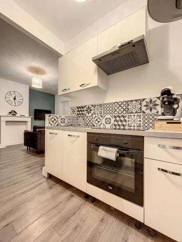 une cuisine avec des armoires blanches et un four à plaques de cuisson dans l'établissement Coeur de ville, T2 cosy & élégant, à Dunkerque