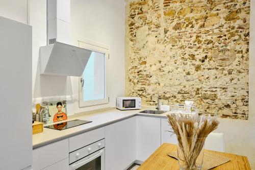 a kitchen with white cabinets and a brick wall at Apartamento La Perla Little Apartments in Cádiz