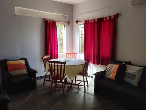 sala de estar con mesa, sillas y cortinas rojas en Casa Vacacional MIA, en Piriápolis
