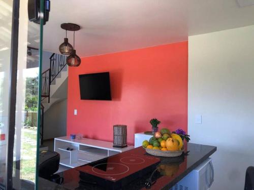 una habitación con una pared roja con un bol de fruta en una mesa en Jardim das Emerências - Búzios, en Búzios