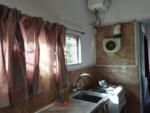 una pequeña cocina con fregadero y ventana en Casa Vacacional MIA, en Piriápolis