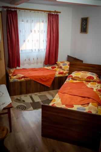 a bedroom with two beds and a window with red curtains at Vila Diana in Vartop