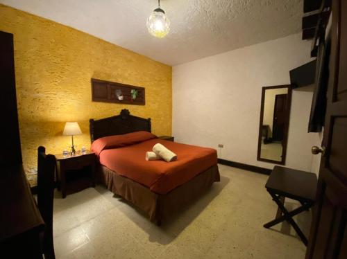a bedroom with a bed and a table with a lamp at Hotel Posada San Pedro in Antigua Guatemala