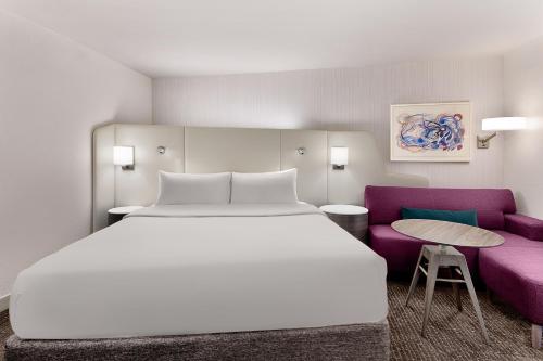 a bedroom with a large bed and a purple couch at Crowne Plaza Atlanta Perimeter at Ravinia by IHG in Atlanta
