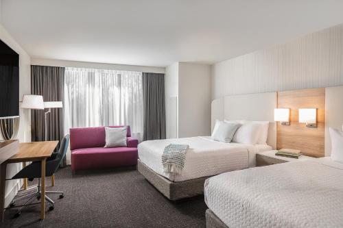 a hotel room with two beds and a pink chair at Crowne Plaza Atlanta Perimeter at Ravinia, an IHG Hotel in Atlanta