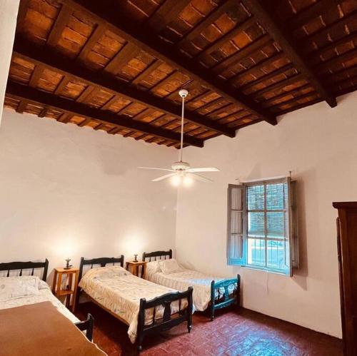a bedroom with two beds and a ceiling fan at El Cencerro - Casa de Campo in Villa Lía