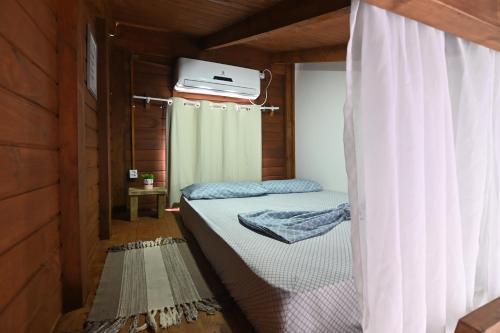 Cette petite chambre comprend 2 lits et un rideau. dans l'établissement Chalé pertinho de Jurerê Ch1, com Fire Stick, à Florianópolis