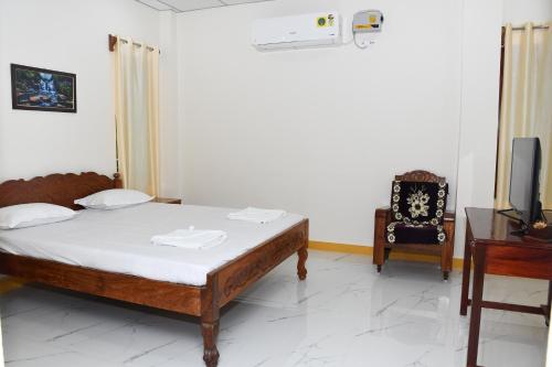 a bedroom with a bed and a chair and a tv at coco view in Port Blair