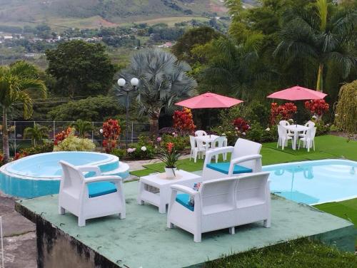 eine Gruppe von Stühlen und Tischen und ein Pool in der Unterkunft La Casa de Yeny in Borrero Ayerbe