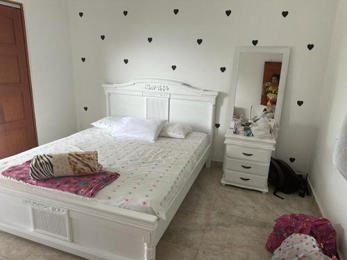 Schlafzimmer mit einem weißen Bett und einem Spiegel in der Unterkunft La Casa de Yeny in Borrero Ayerbe