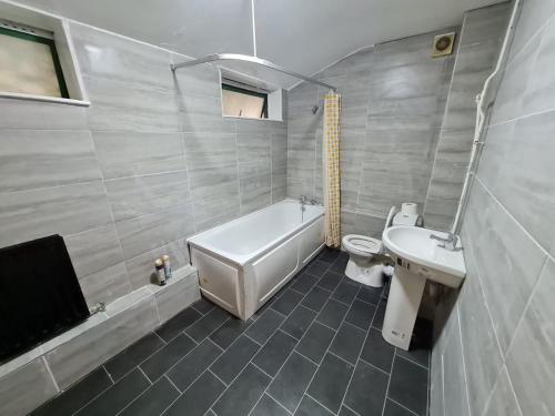 a bathroom with a tub and a toilet and a sink at London E2 Rooms in London