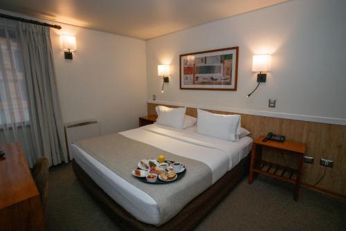 a hotel room with a bed with a tray of food on it at Hotel Don Luis Puerto Montt in Puerto Montt