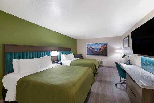 a hotel room with two beds and a flat screen tv at Quality Inn Alpine in Alpine