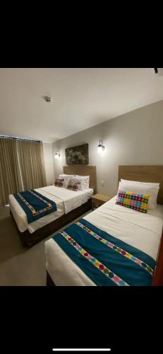 um quarto de hotel com duas camas com almofadas coloridas em Apartamento no centro com lazer! em Pirenópolis