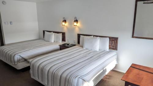 duas camas num quarto de hotel com paredes brancas em High Desert Inn em Salina