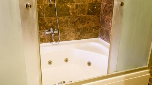 a bath tub with a shower in a bathroom at Hotel Labella Bergama in Bergama