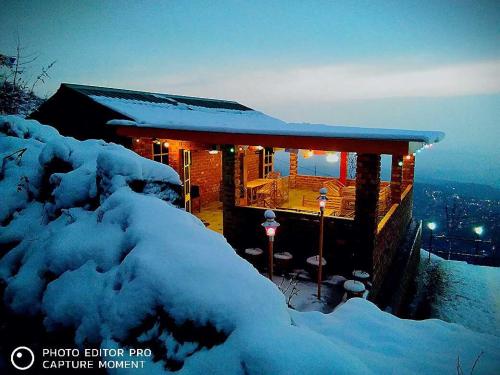 ein Haus mit Schnee in der Nacht und Lichtern in der Unterkunft OYO Rage Roodies Camping in McLeod Ganj