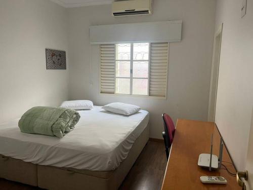 - une chambre avec un lit, un bureau et une fenêtre dans l'établissement Residencial Bem-te-vi, à Matão