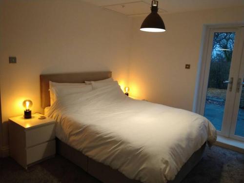 a bedroom with a bed with white sheets and a window at Mountain Lodge with magical views in Pentyrch