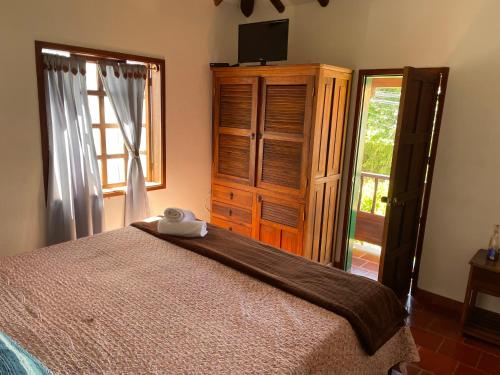 a bedroom with a bed and a dresser and a window at Hostal El Pino in Villa de Leyva
