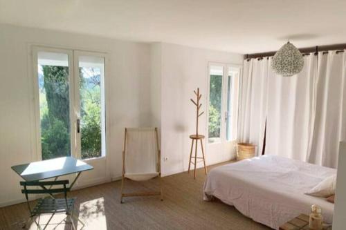 Schlafzimmer mit einem Bett, einem Tisch und Fenstern in der Unterkunft Panorama d'exception, piscine, terrain de pétanque in La Roche-sur-le-Buis