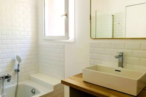 ein Badezimmer mit einem Waschbecken, einer Badewanne und einem Spiegel in der Unterkunft Panorama d'exception, piscine, terrain de pétanque in La Roche-sur-le-Buis