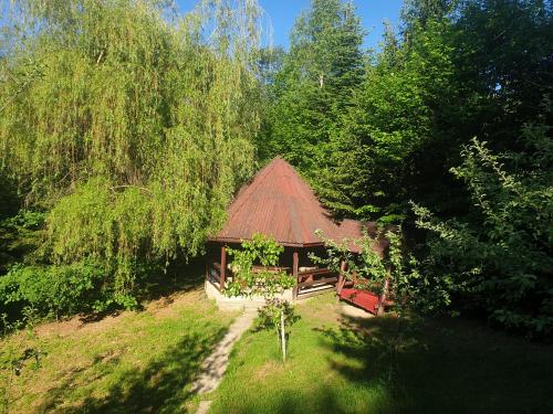 a cabin with a red roof in the middle of a forest at Casa Lacramioara in Sâmbăta de Sus