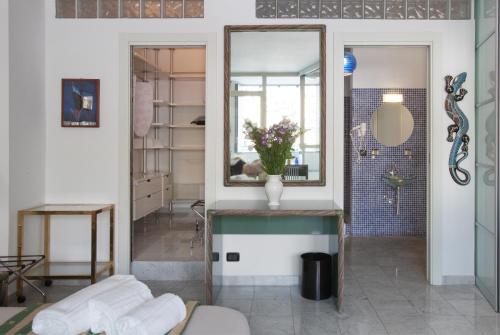 un baño con espejo y un jarrón de flores en un mostrador en Acquario Genova Suite, en Génova