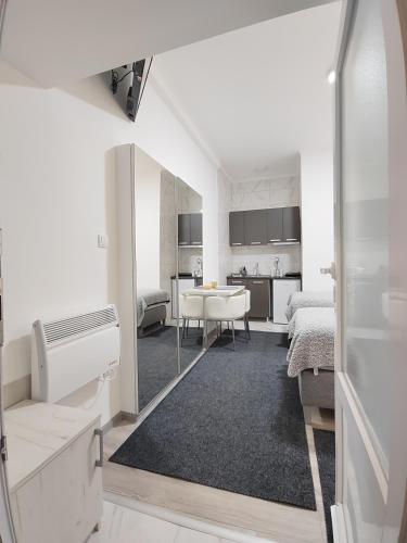 Apartman Centar Ivanjica في إيفانييتسا: غرفة بيضاء فيها سرير وطاولة فيها