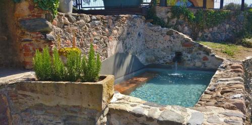 uma pequena piscina de água numa parede de pedra em Masia Can Bachs em Sant Pere de Vilamajor