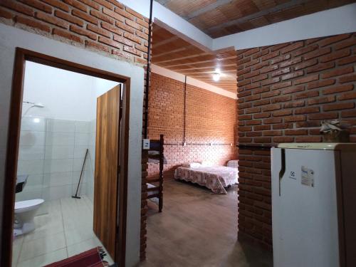 Habitación con pared de ladrillo y nevera. en Pousada do Chicó, en São Roque de Minas