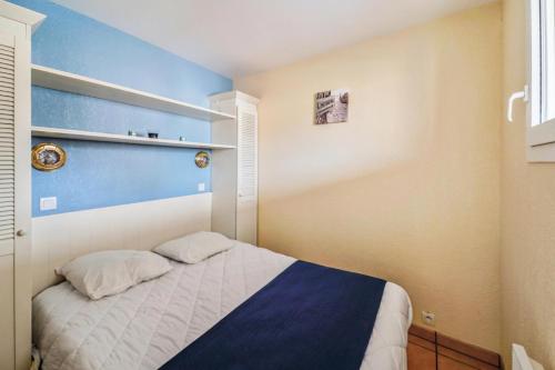 - une petite chambre avec un lit et un mur bleu dans l'établissement Résidence Bleu Marine - maeva Home - Appartement 2 pièces 4 personnes Confort MAE-7359, à Lacanau