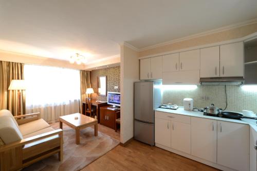 a kitchen with white cabinets and a living room at Flower Hotel Ulaanbaatar in Ulaanbaatar
