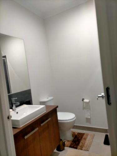 a bathroom with a sink and a toilet and a mirror at Maha Melton Homestay in Melton South