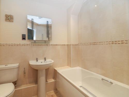 a bathroom with a sink and a toilet and a bath tub at Y Enciliad in Rhosneigr