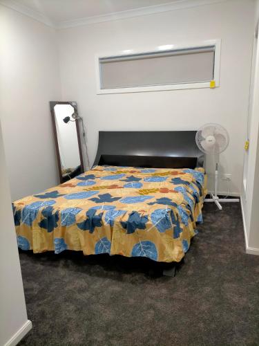 1 dormitorio con 1 cama con edredón en Maha Melton Homestay en Melton South