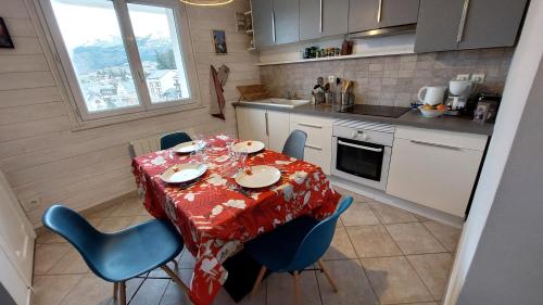 une cuisine avec une table, des chaises et un tissu de table dans l'établissement Appartement centre Villard de Lans, 49 m2 2 pièces plus cuisine 4/6 personnes, à Villard-de-Lans