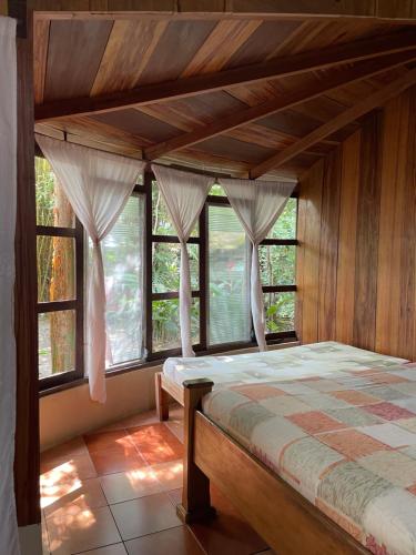1 dormitorio con cama con dosel y ventanas en Hotel Ecológico Cabañas del Lago, en El Estor