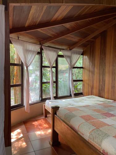 a bedroom with a canopy bed with windows at Hotel Ecológico Cabañas del Lago in El Estor
