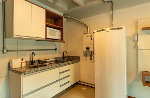 a kitchen with white cabinets and a refrigerator at Apartamento com garagem no Centro de Guaramiranga in Guaramiranga