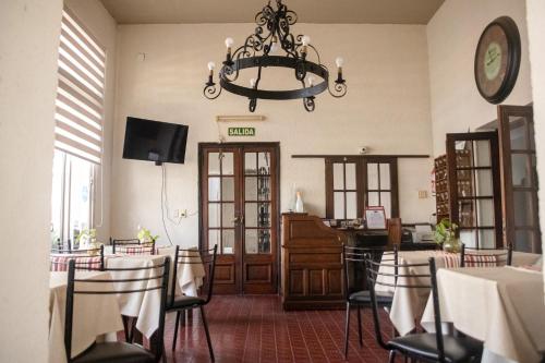 un comedor con mesas y sillas y una lámpara de araña en Hotel Abadia en Gualeguaychú