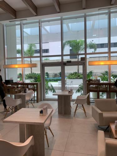 restauracja ze stołami i krzesłami oraz dużymi oknami w obiekcie Estúdio perfeito w mieście Kurytyba