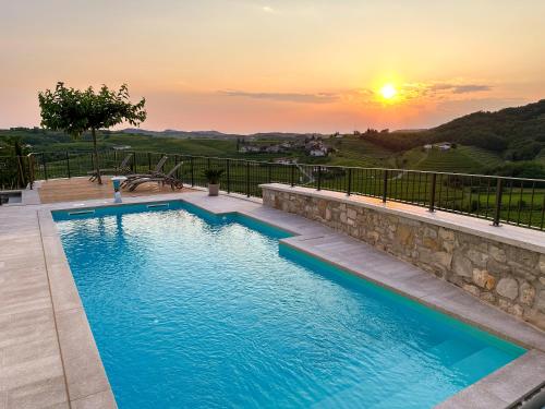 una piscina con tramonto sullo sfondo di A Luxury 100m2 Apartment in a Chic Vineyard Villa - Ca' S. Lorenz a Dobrovo