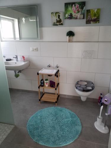 a bathroom with a sink and a toilet and a rug at Ferienwohnung Füssel - NICHT FÜR MONTEURE in Bad Staffelstein
