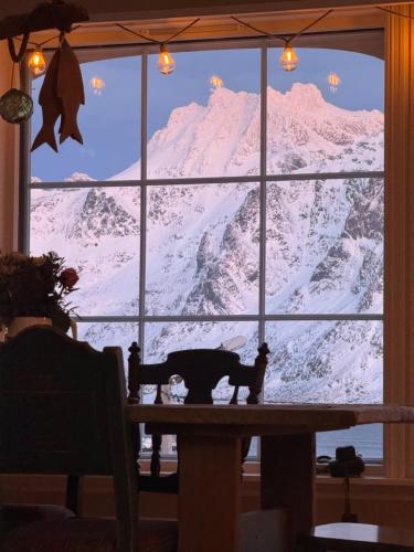 a cat sitting at a table looking out a window at a mountain at Sundet Lofoten Holiday House in Sund