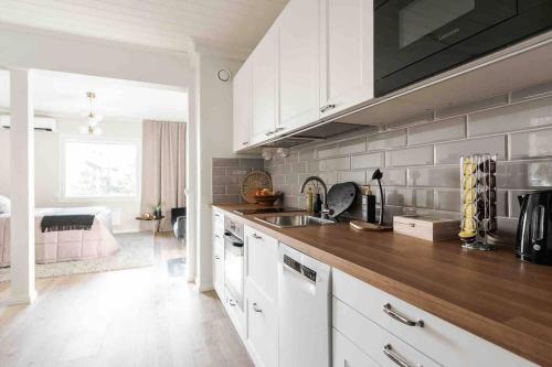 Una cocina con gabinetes blancos y una encimera de madera. en Lakeview retreat in Pispala, en Tampere