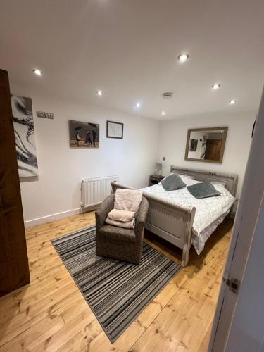 a bedroom with a bed and a chair at Pine cottage with private hot tub in Upper Hulme