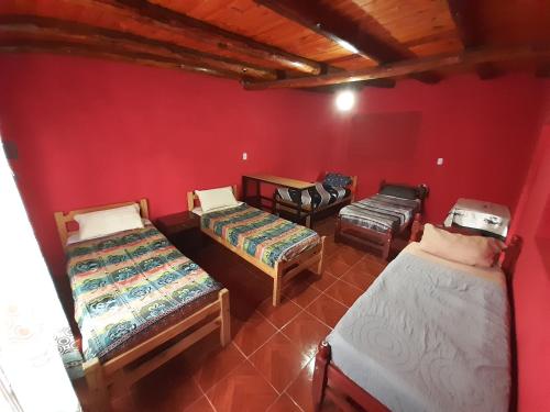 Zimmer mit 3 Betten und einer roten Wand in der Unterkunft Maima Host II in Maimará